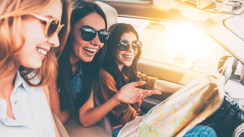 Friends in car with a map laughing