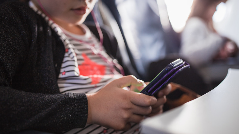 child using phone on plane