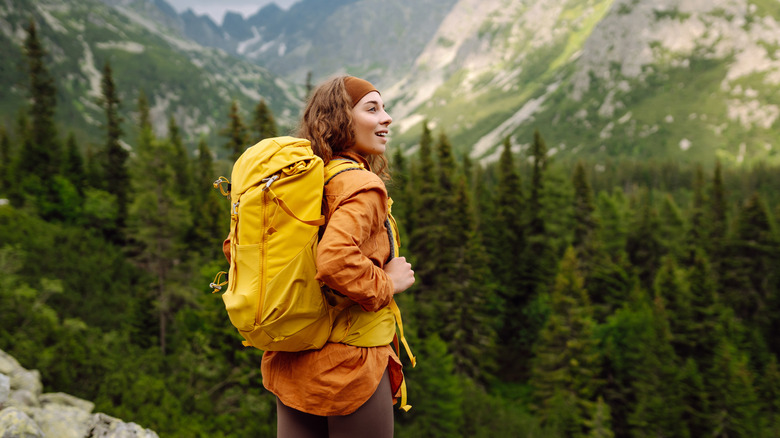 Backpacking woman in front of a forest