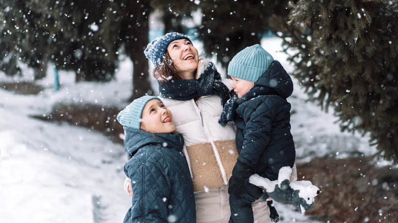 Mother and her children catching snowflakes, smiling