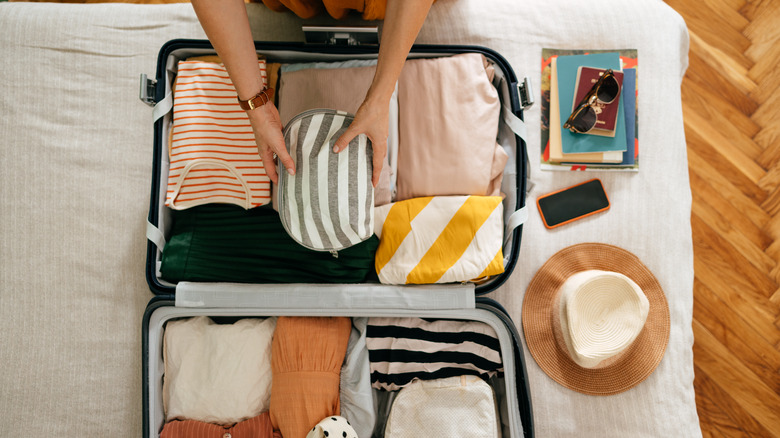 person packing open suitcase