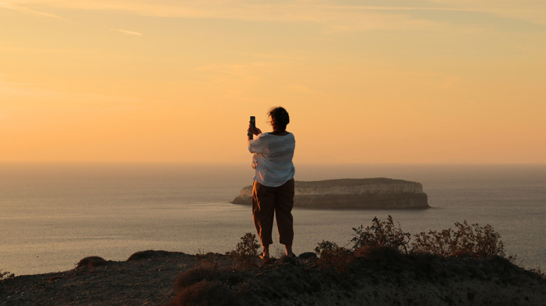 Solo traveler photographing Santorini sunset