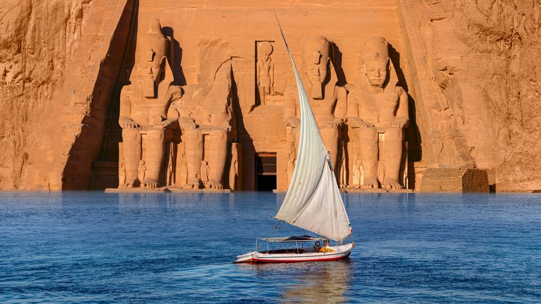 A boat cruising along the Nile, in front of the huge stone statues at Abu Simbel.