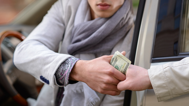 man handing money to valet driver