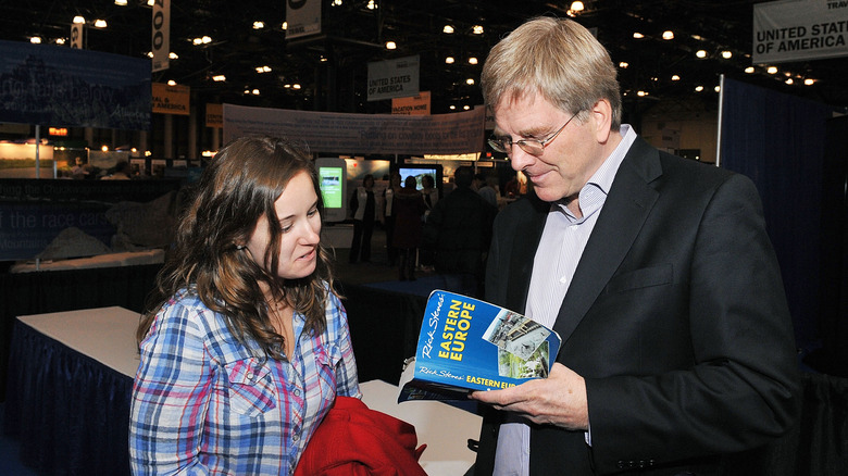 Rick Steves signing a fan's guidebook