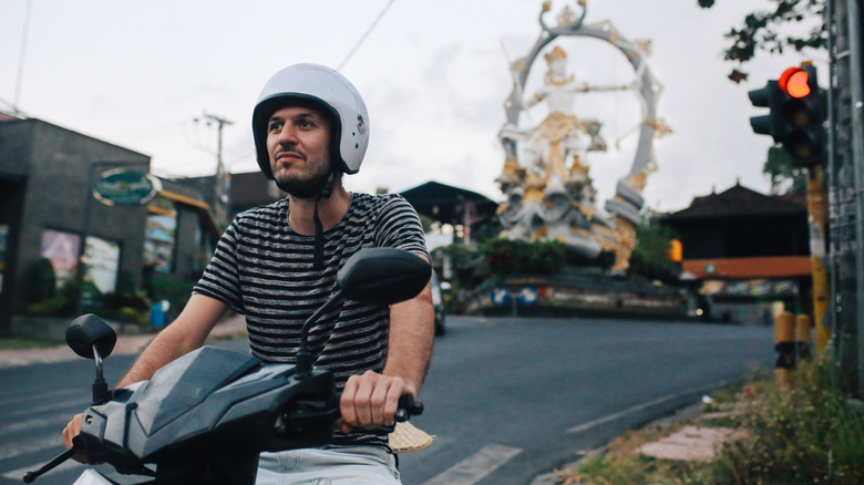 A man wearing a helmet on a scooter in Ubud, Bali