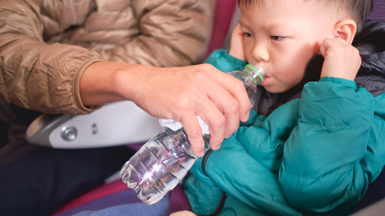 kid drinking water on plane