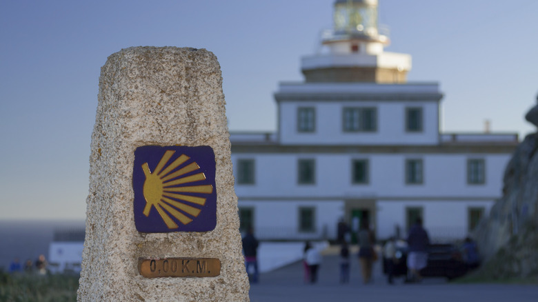 Camino de Santiago marker with faded building in background