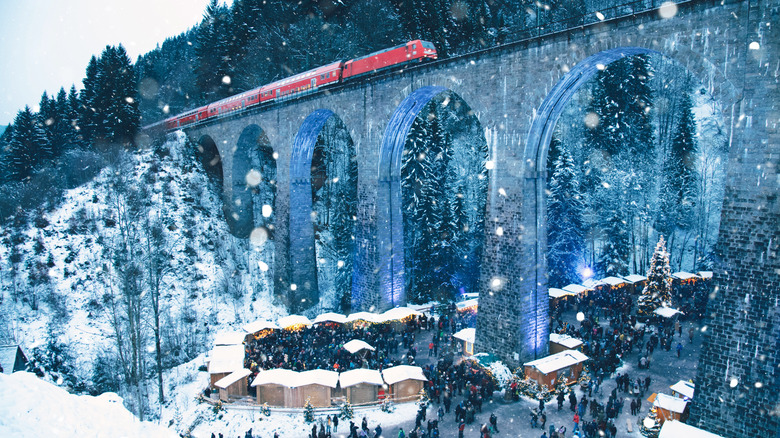 red train on viaduct over wintry market germany