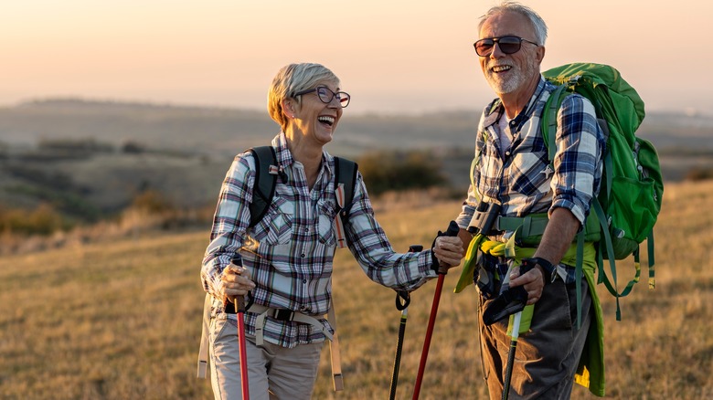 elderly couple smiling with backpacks in nature