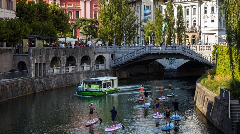 boat and paddleboarders near bridge