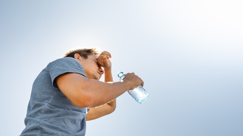 man drinking water on a hot day to avoid dehydration