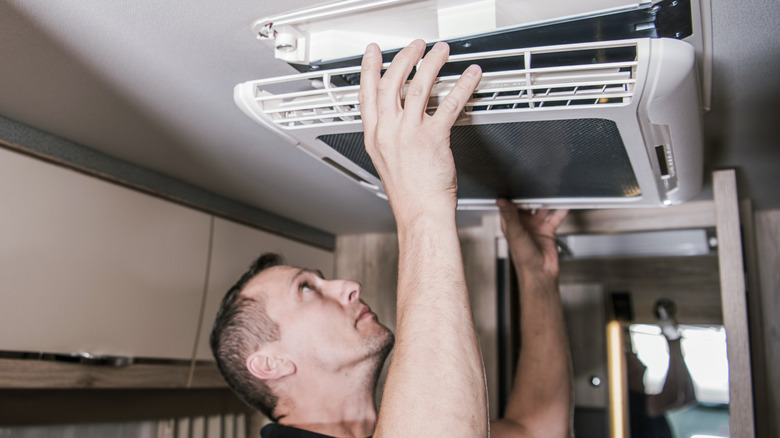 man fixing RV air conditioning