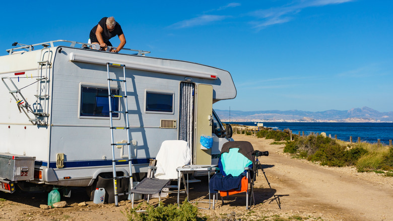 RV owner fixing something while parked at beach