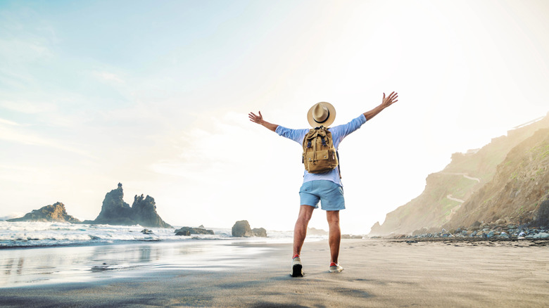 Happy traveler walking onto the beach with open arms