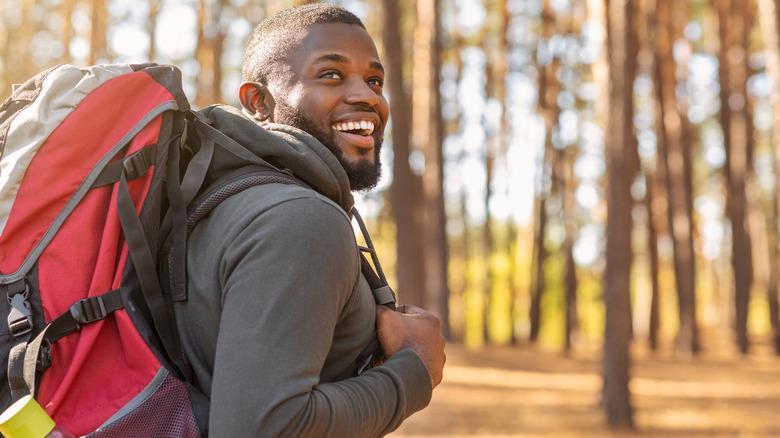 man smiling hiking with backpack