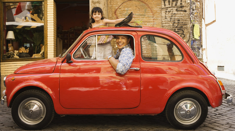 Small red car with two passengers in Italy