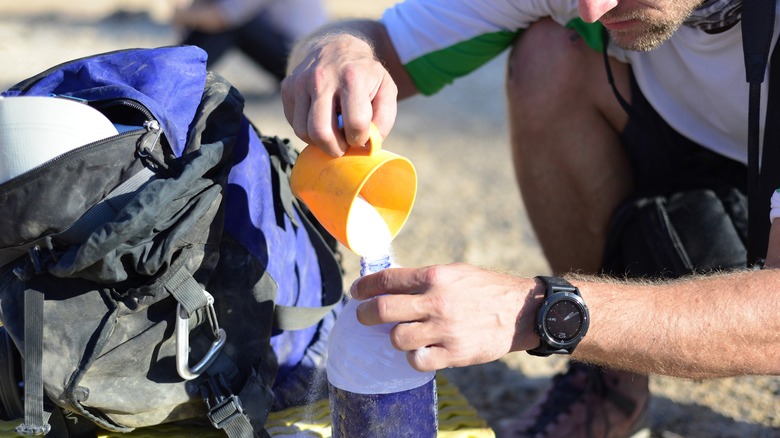 Male hiker adding electrolytes to water