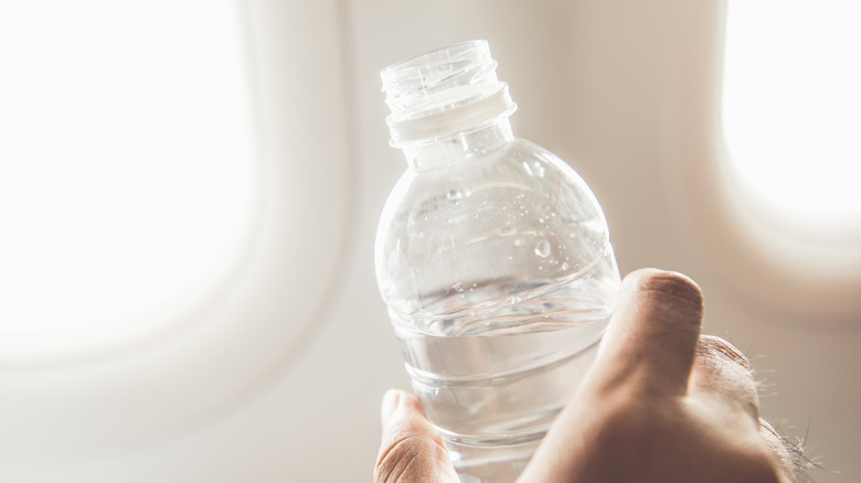 Person drinking water on plane