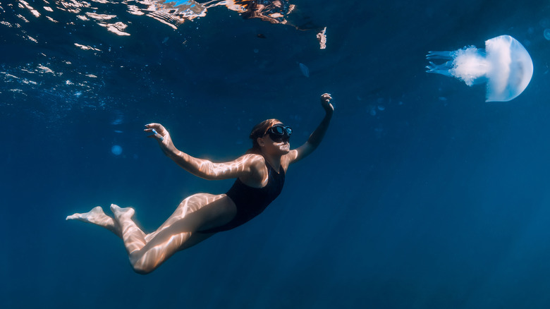 woman swimming underwater with jellyfish