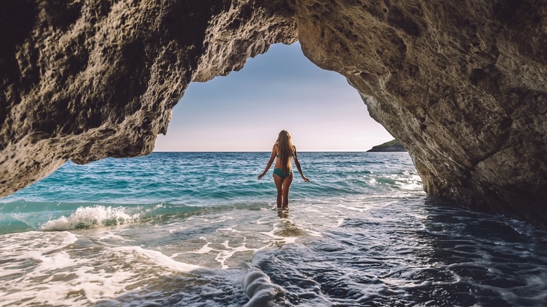 Woman exploring a Gjipe Beach natural cave 