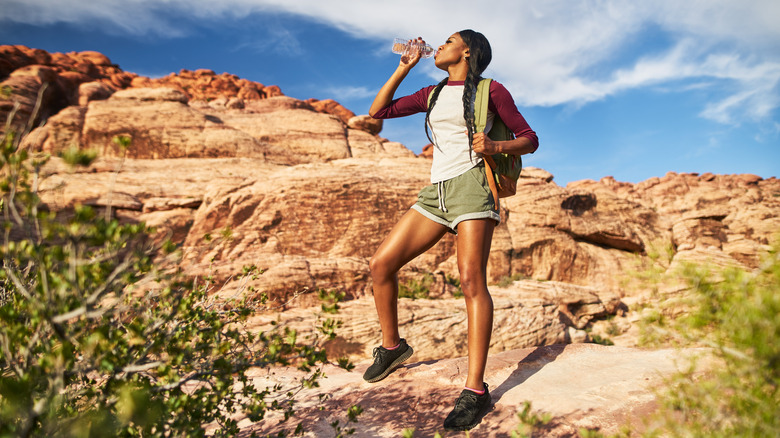 woman drinking water while hiking