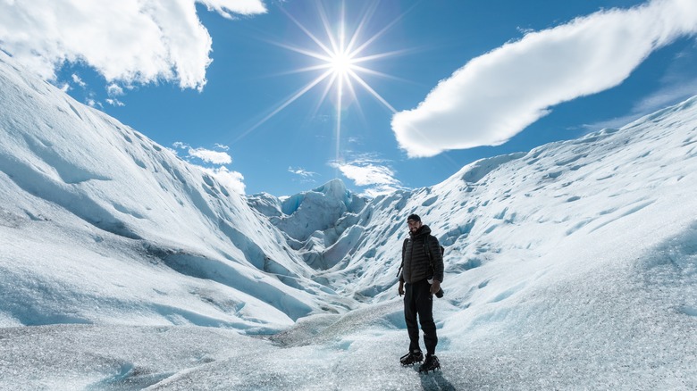 man poses on sunny glacier