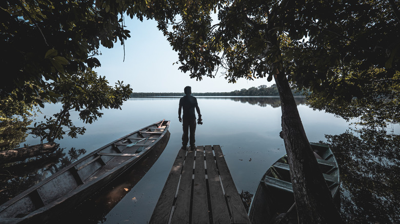 Traveler overlooking a quiet lake in Tambopata National Reserve