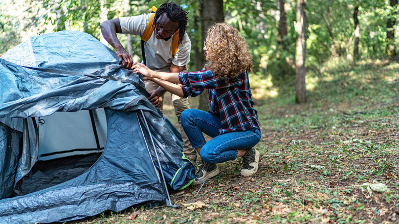 A man and woman setting up a tent