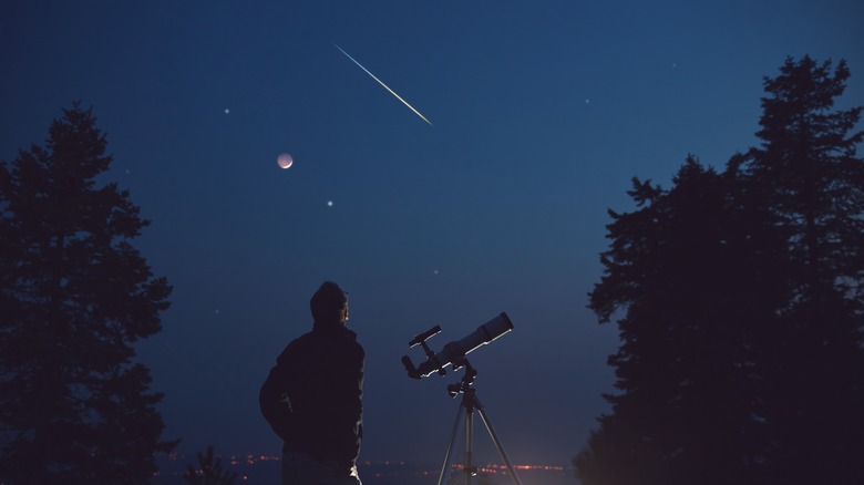 Man with telescope at night