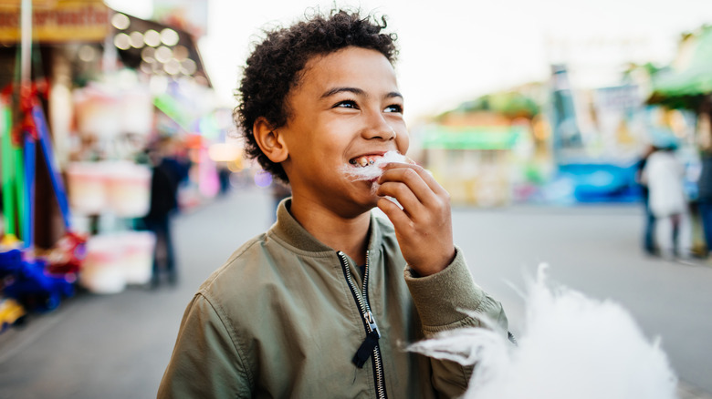 Child eating cotton candy at theme park