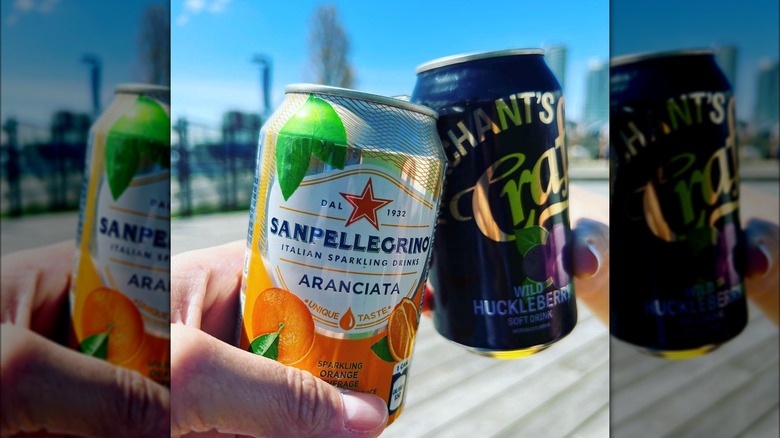 Two hands toasting with drink cans