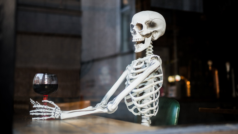 Skeleton drinking wine in pub in Britain