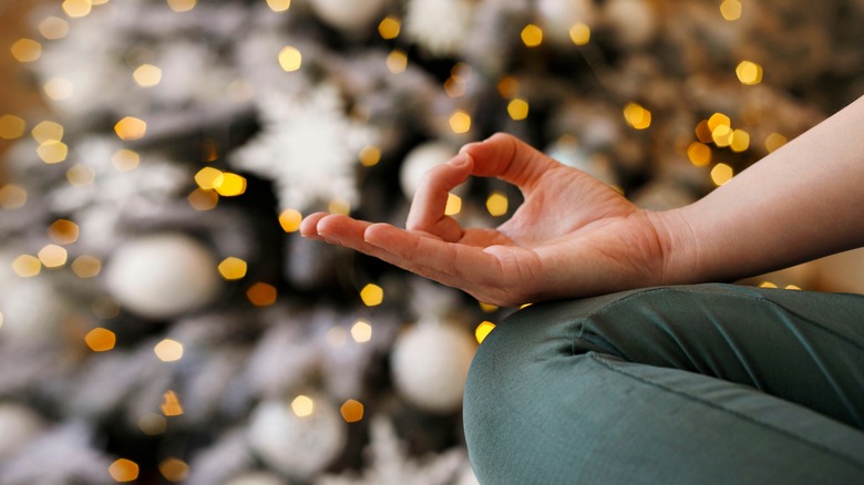 Woman meditating by Christmas tree