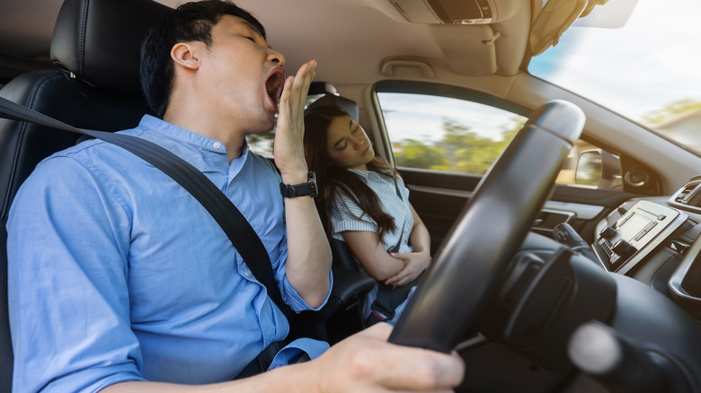 yawning driver and sleeping passenger in car
