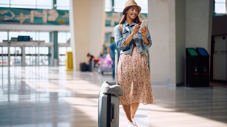 Smiling traveler texting from airport