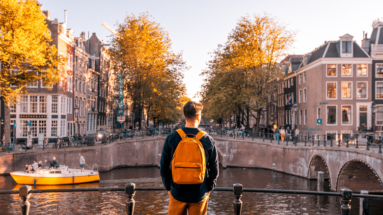 Solo traveler gazing out at the canals of Amsterdam in the fall