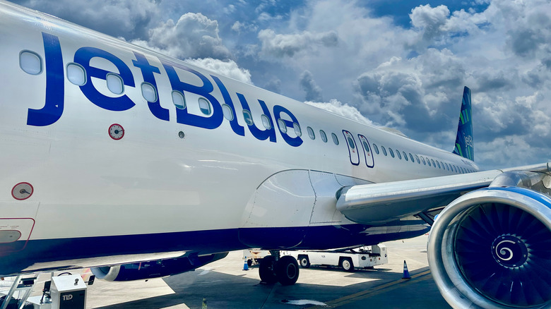 closeup of JetBlue plane fuselage with clouds in background