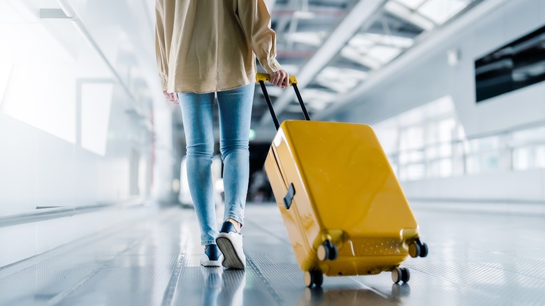 Passenger rolling suitcase through airport