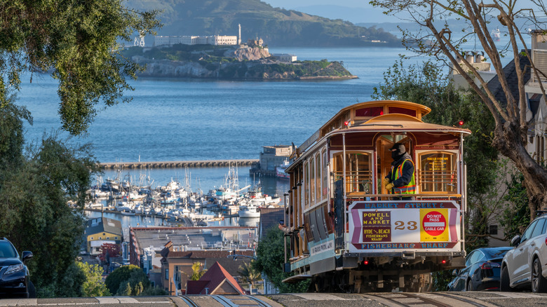 A San Francisco street car on a steep street with Alcatraz in the background