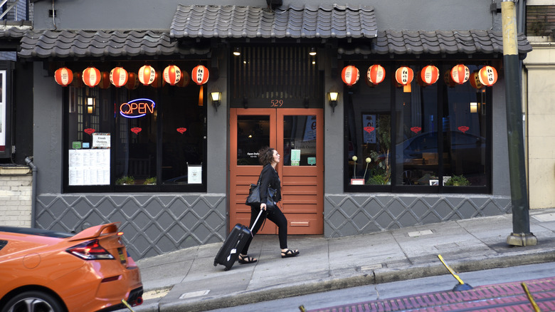 A woman pulls her suitcase up a steep hill in San Francisco