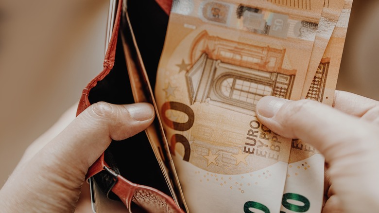Traveler placing euros into a wallet