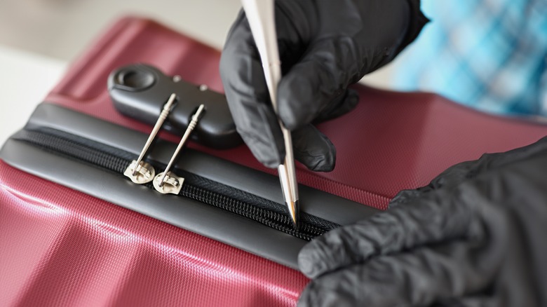 person breaking into suitcase zipper