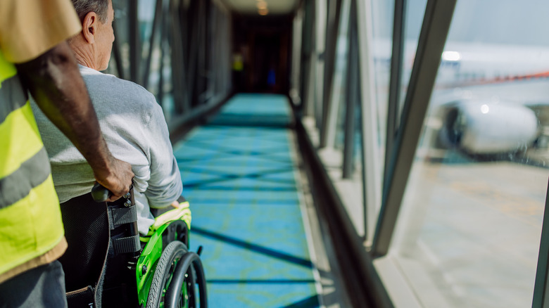 Airport worker helping passenger on wheelchair