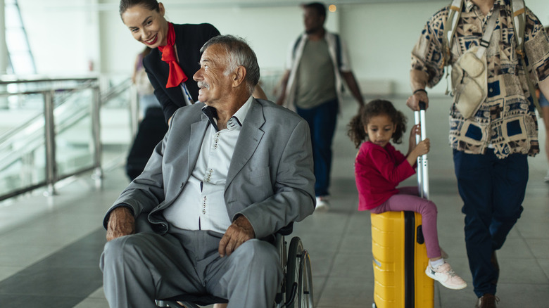 Flight attendant pushing senior traveler in wheelchair