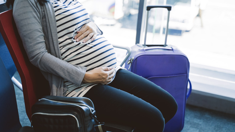Pregnant woman seated at airport while traveling