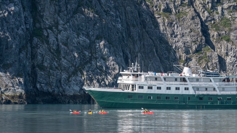 People kayaking around small cruise ship