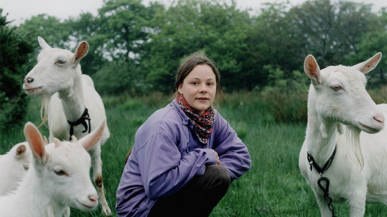 Woman beside goats on grass