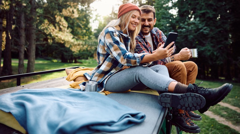 couple looking at a smart phone at a campsite