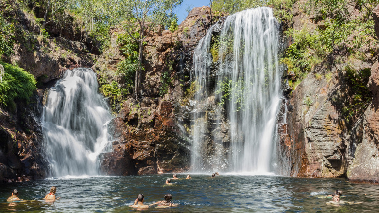 waterfalls into pond with swimmers